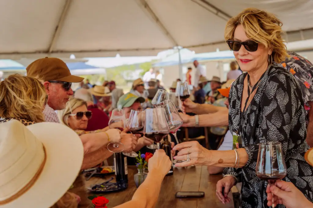 Guests raising glasses under the tent at an Uplift Vineyard release party